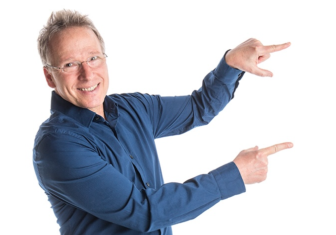 Dave Nelsen in a dynamic pose, wearing a blue shirt and pointing to his left with both hands, with a warm, engaging smile. The background is pure white, emphasizing his energetic gesture and cheerful expression.